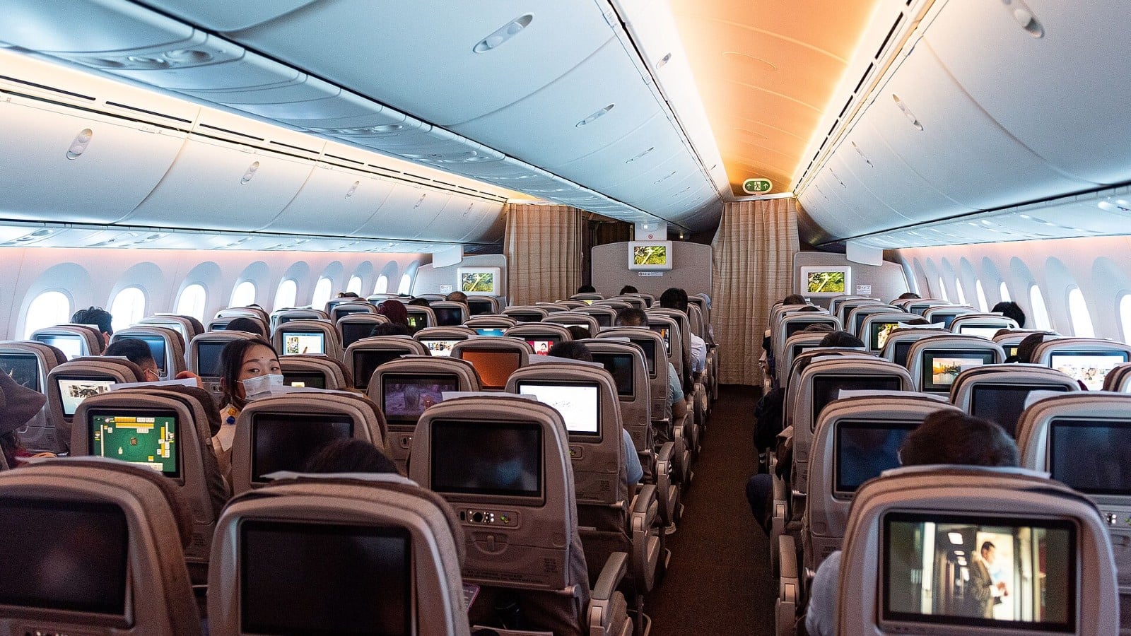 Why Airlines Dim the Cabin Lights for Takeoff and Landing Airliner economy cabin with dimmed mood lighting and passengers seated
