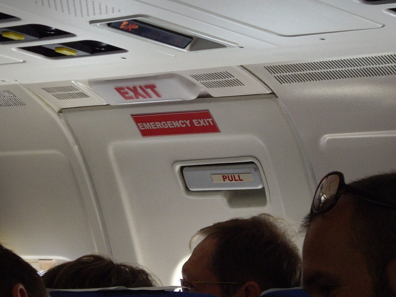 Illuminated EXIT sign and emergency exit handle inside an airliner cabin