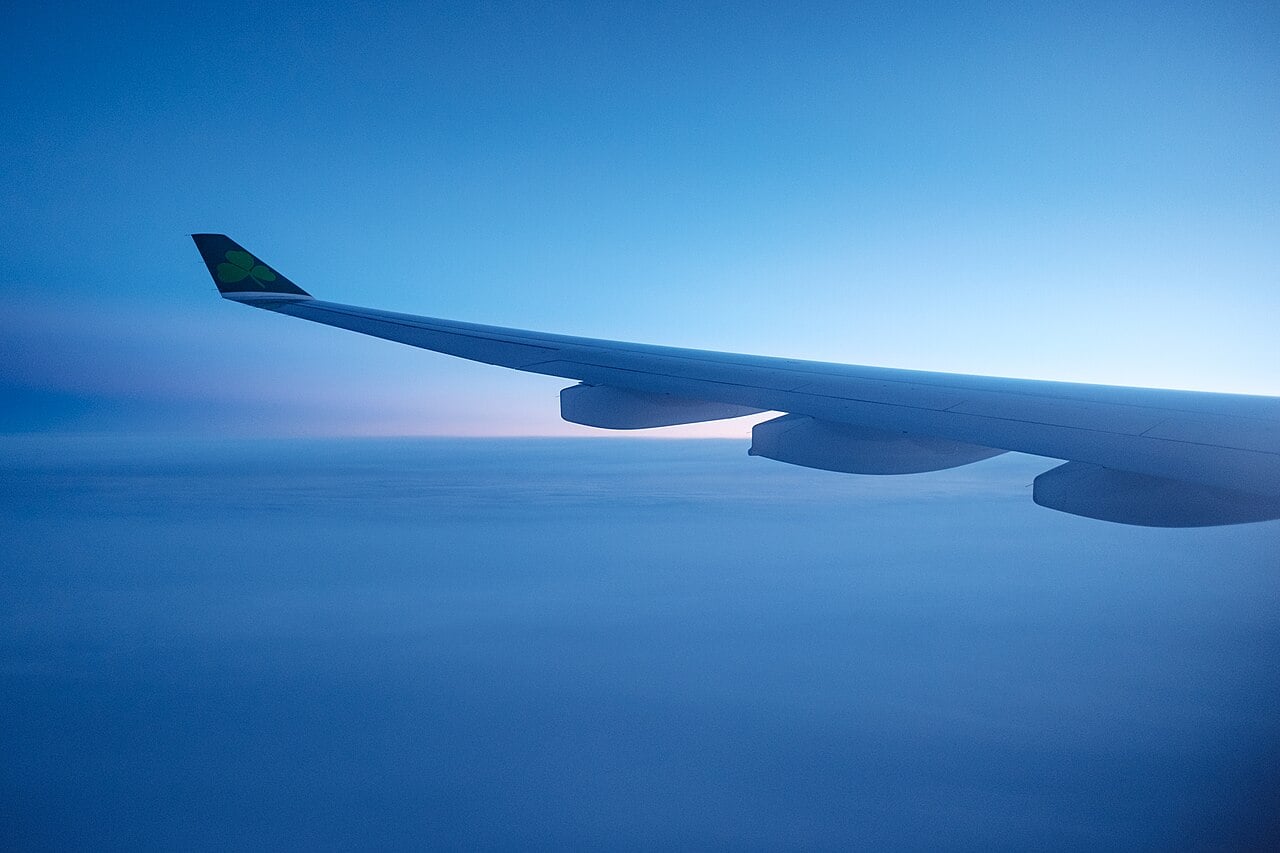 Airliner wing above the clouds in blue dawn light