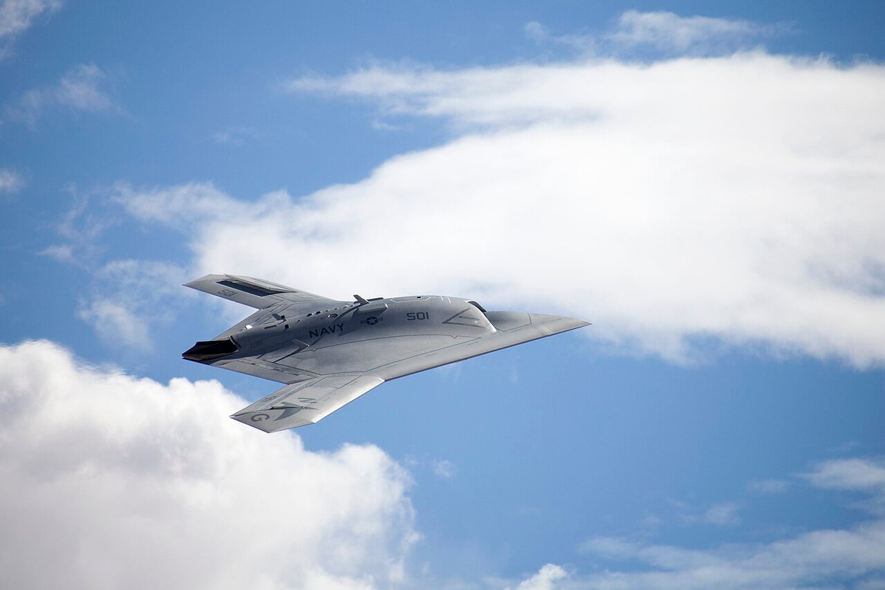 A US Navy X-47B unmanned combat air system banking, showing its tailless flying-wing planform