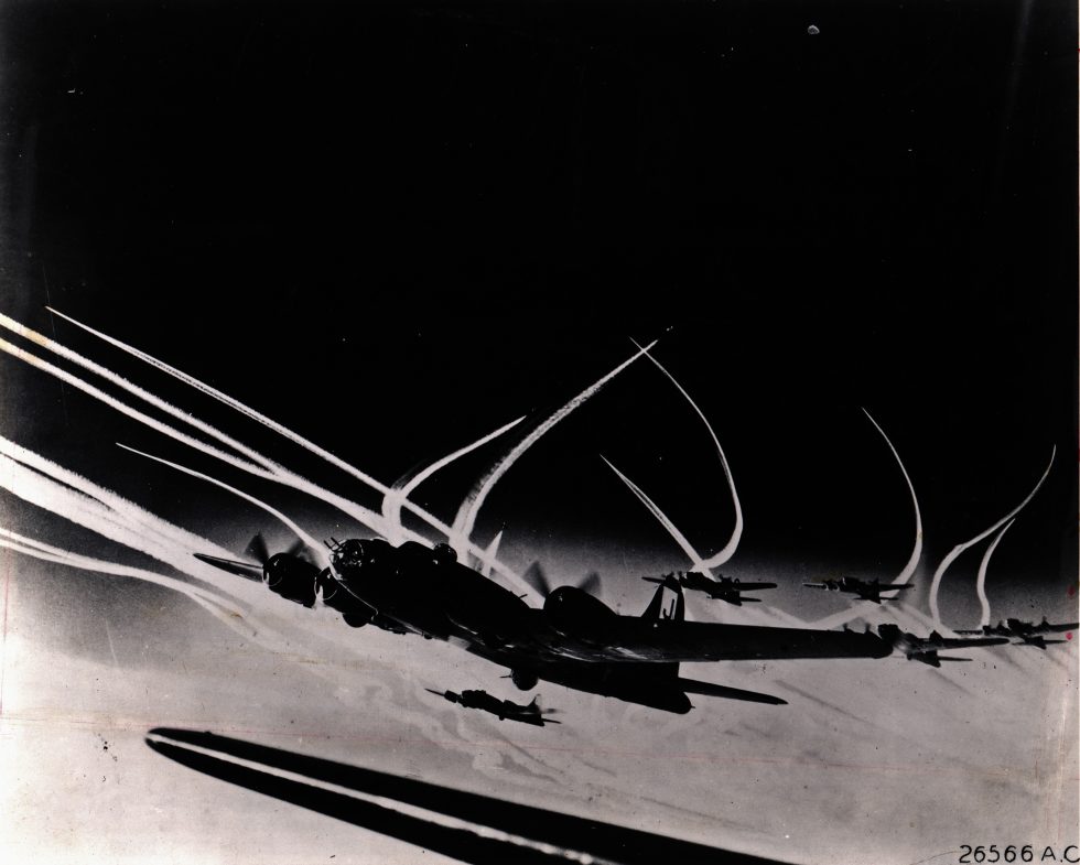 B-17s in a tight formation, contrails streaming the combat box that pooled their defensive fire.