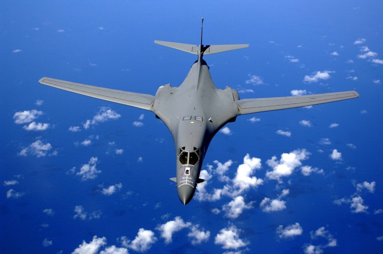 A B-1B Lancer over the Pacific wings swept for high-speed cruise.
