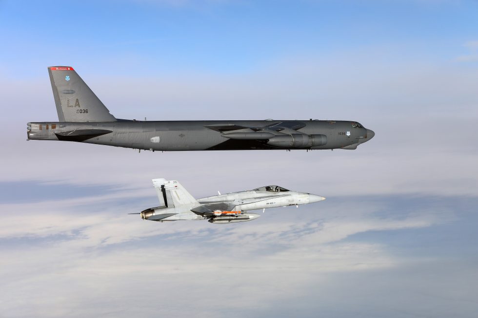 A Finnish Air Force F-18C Hornet flies alongside a US Air Force B-52  the Ilmavoimat has flown the Hornet since the 1990s.