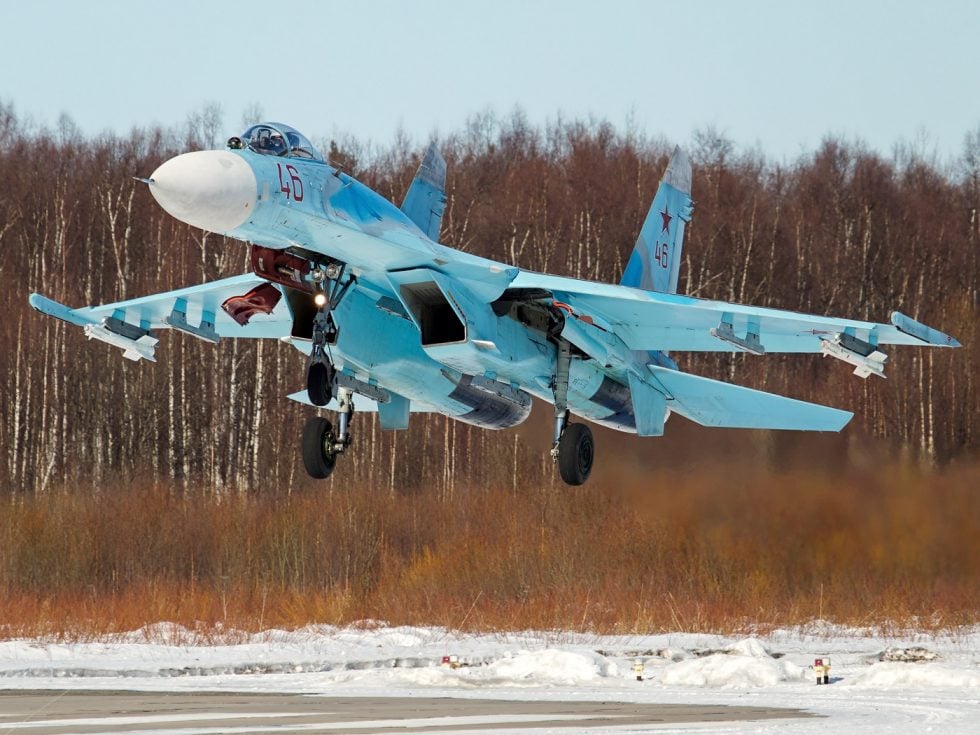 A Russian Air Force Su-27P banking in flight over the countryside.