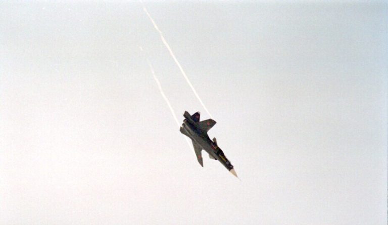 The S-37 climbing away under power during the flight-test years, a contrail streaming behind it.