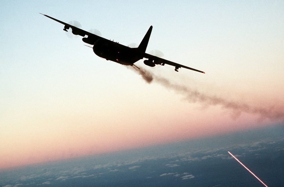 An AC-130 firing broadside at dusk  the side-firing guns that define the gunship.