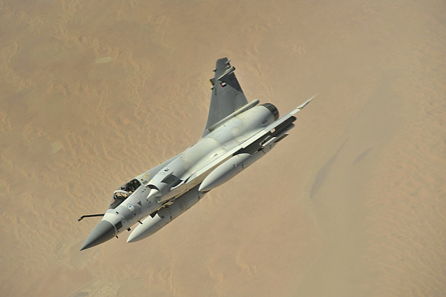 Dassault Mirage 2000 delta-wing fighter banking over desert in flight