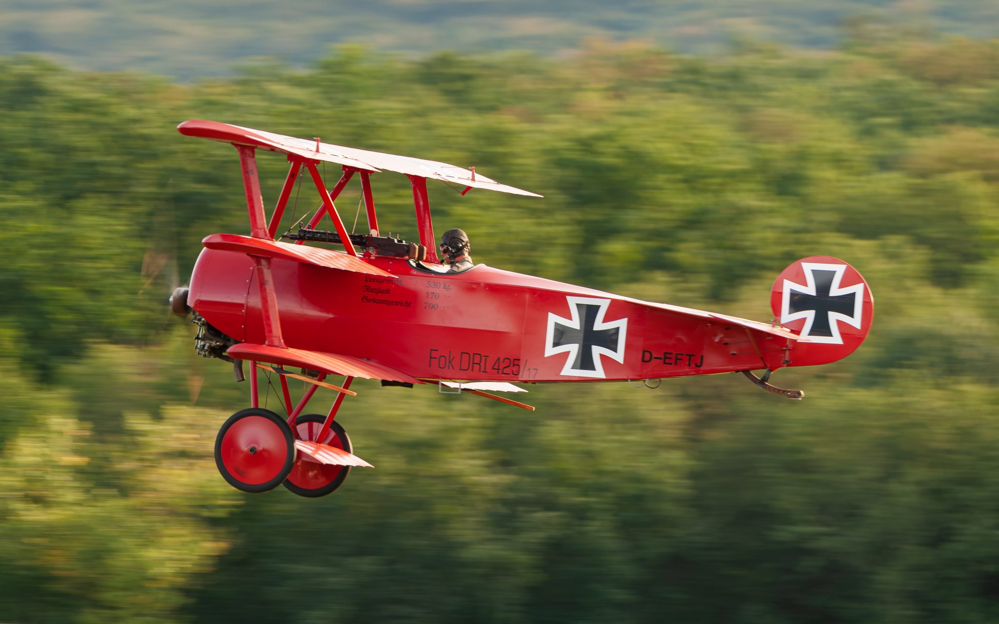 A Fokker Dr.I Triplane flying replica in the air, showing its three stacked wings