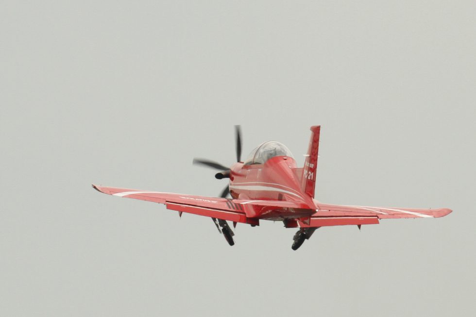 A PC-21 banking in flight, its five-blade graphite propeller catching the light.